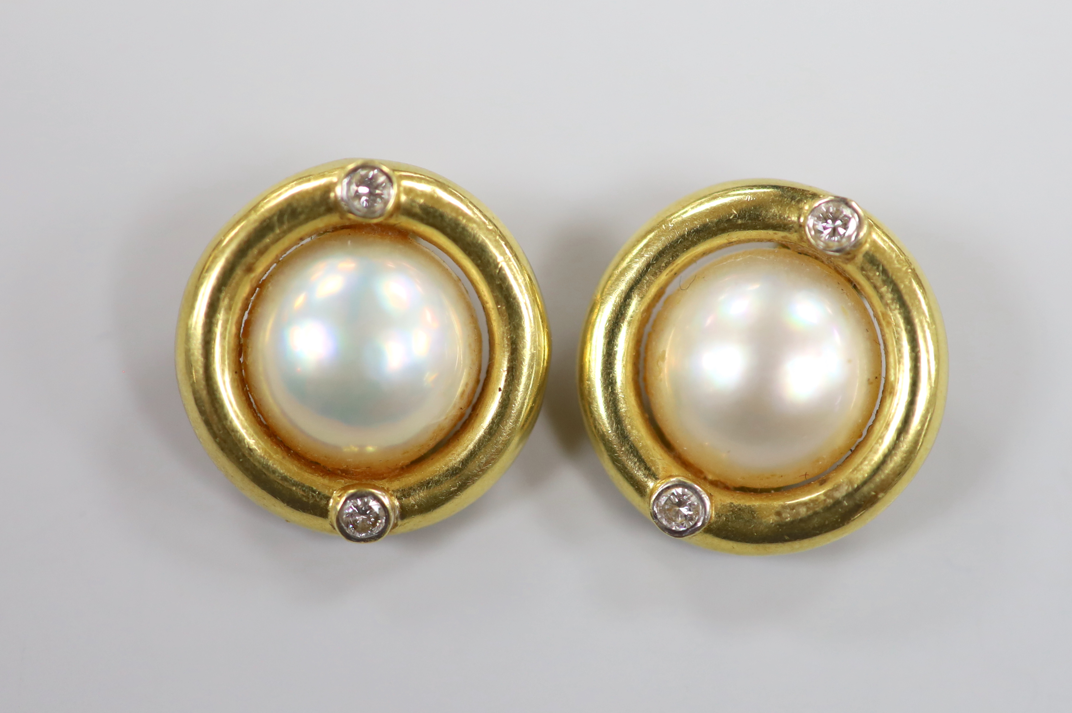 A modern pair of 750 yellow metal, mabe pearl and two stone diamond set circular ear clips, 20mm, gross weight 11.6 grams.